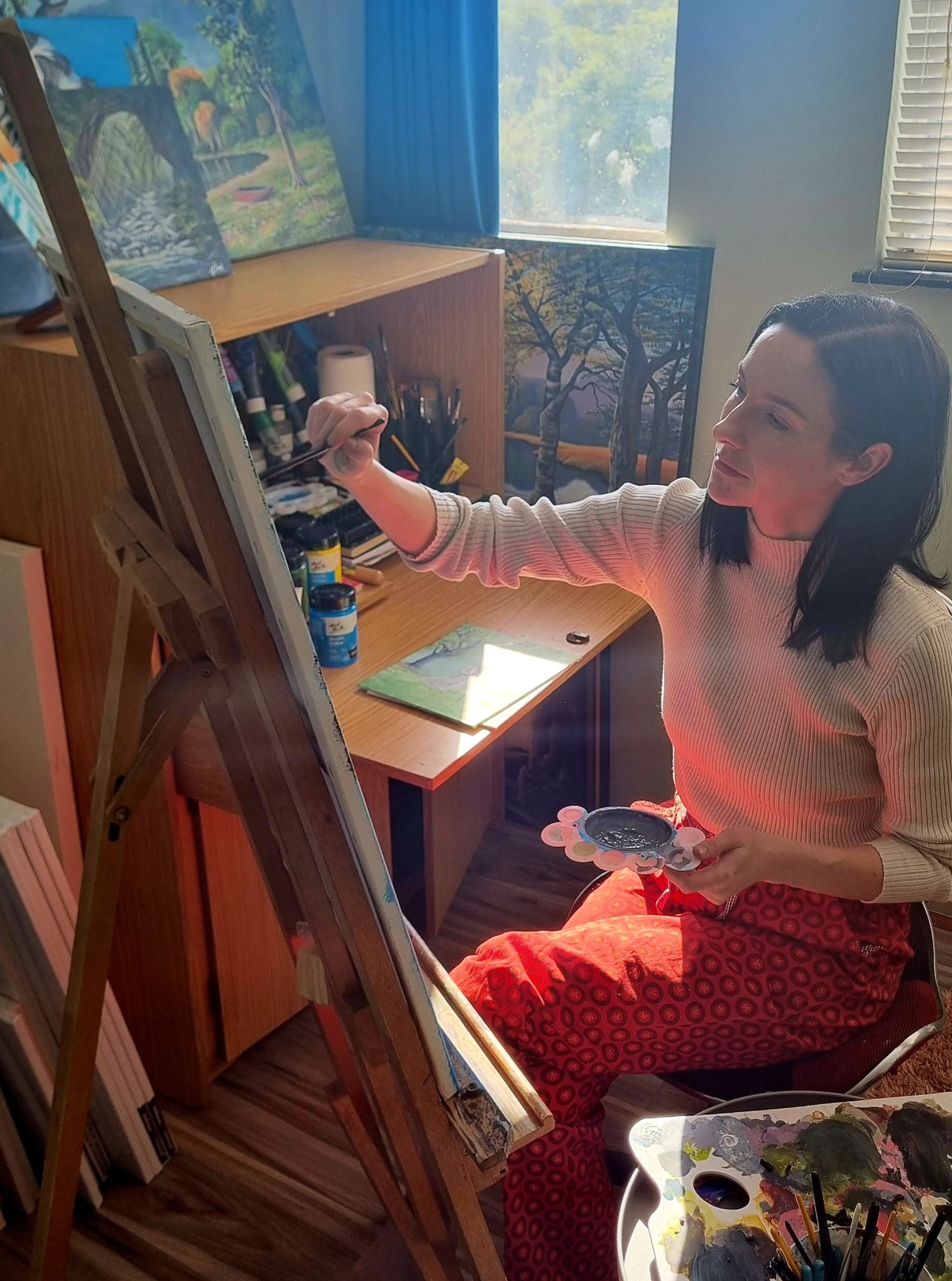Melinda painting at the easel in her sunlit studio